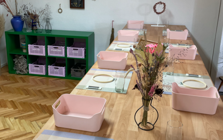 Eine große Werkbank mit rosa Körben und Werkzeug für einen Trockenblumen Workshop.