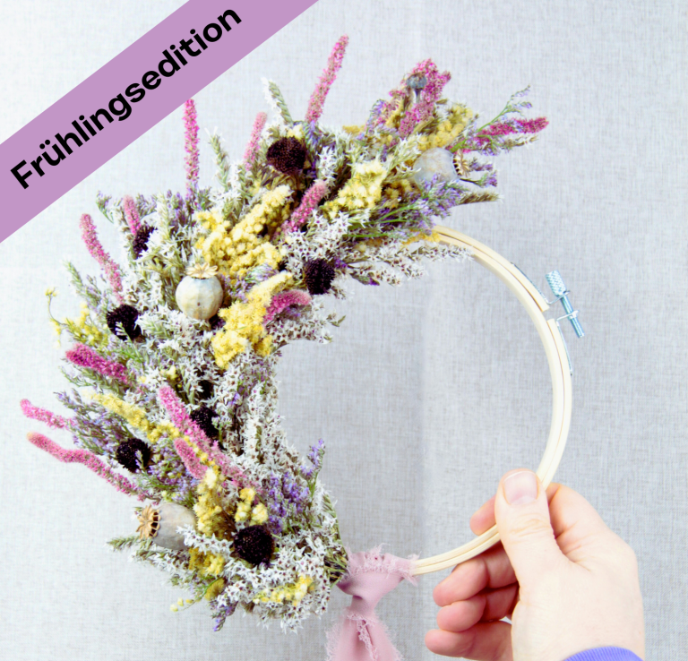 Hand haltend, Holzring mit getrockneten Blumen in lila und grün.