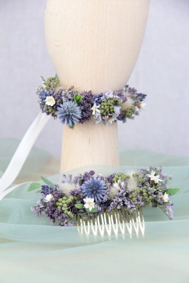 Haarschmuck mit lila und weißen Blumen, dekoriert mit zarten grünen Blättern.