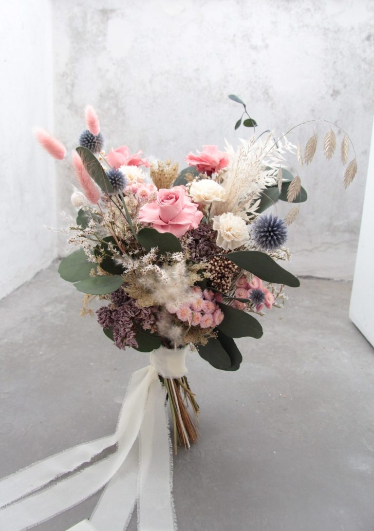 Weiße Blumenarrangement in einem Topf auf einem hellen Untergrund.