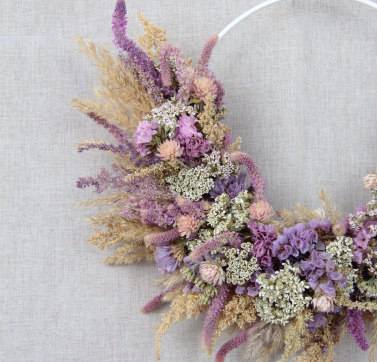 Hand haltend, Holzring mit getrockneten Blumen in lila und grün.