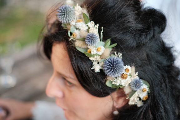 Frau mit einem Blumenkranz aus verschiedenen Pflanzen und kleinen Blüten.