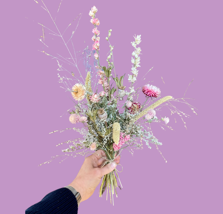 Hand aus Holz präsentiert einen Haarkranz aus Trockenblumen mit bunten Akzenten und Schleifen.